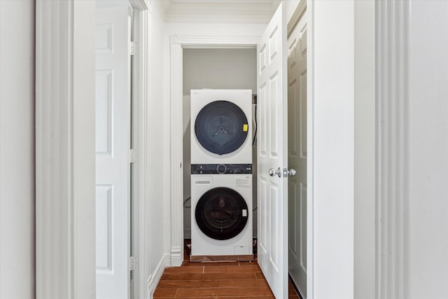 laundry room with stacked washer and dryer, laundry area, dark wood-style flooring, and ornamental molding