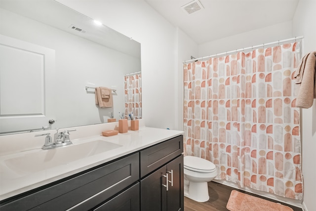 full bath featuring visible vents, vanity, toilet, and wood finished floors