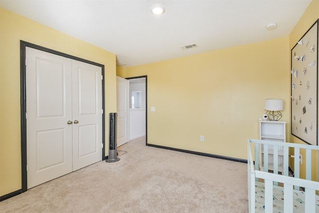 unfurnished bedroom with a closet, visible vents, light carpet, and baseboards