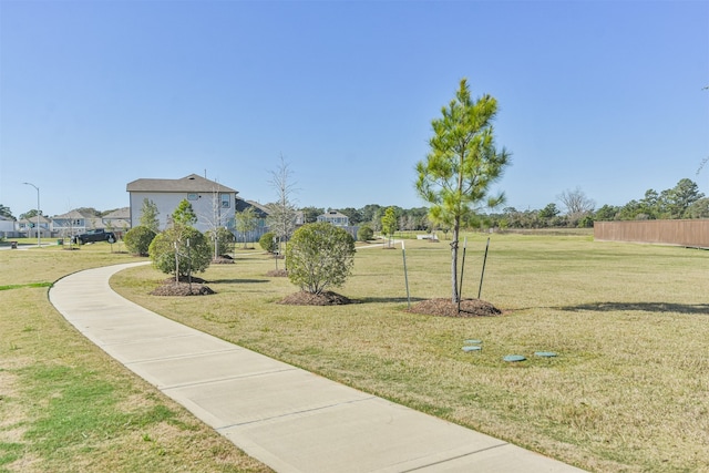 view of community featuring a residential view, a lawn, and fence