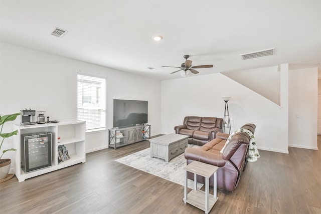 living room with a ceiling fan, baseboards, visible vents, and wood finished floors