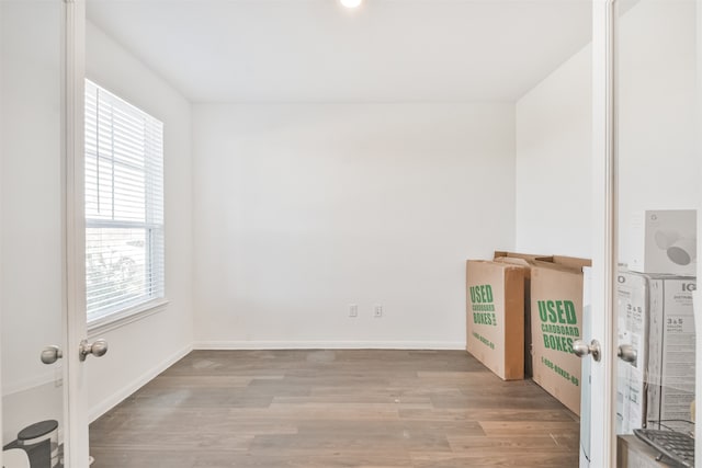 spare room featuring baseboards and wood finished floors