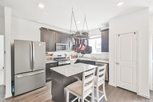 kitchen featuring appliances with stainless steel finishes, a sink, light wood-style flooring, and a kitchen island