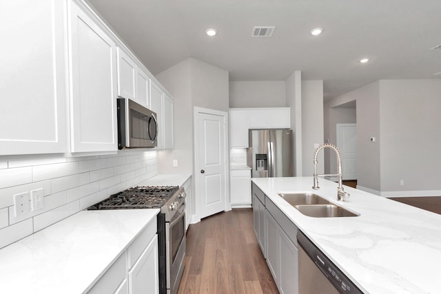 kitchen with visible vents, dark wood-style flooring, light stone countertops, stainless steel appliances, and a sink