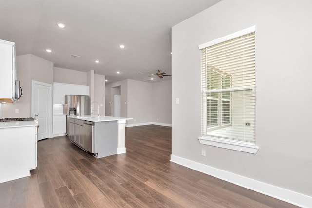 kitchen featuring ceiling fan, light countertops, appliances with stainless steel finishes, an island with sink, and dark wood finished floors