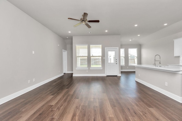 unfurnished living room with dark wood-style floors, recessed lighting, and a sink