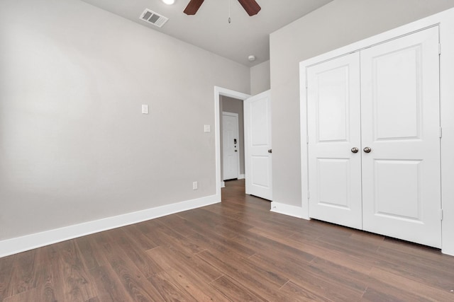 unfurnished bedroom featuring dark wood-style flooring, a ceiling fan, visible vents, baseboards, and a closet