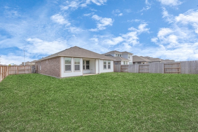 back of house with brick siding, a lawn, and a fenced backyard