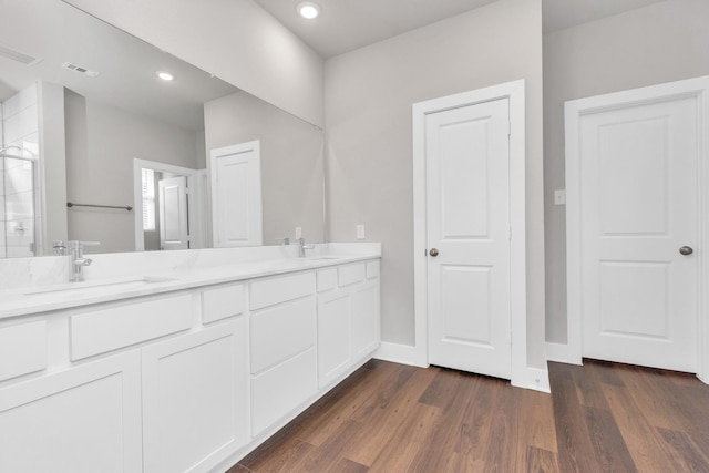 bathroom featuring double vanity, wood finished floors, a sink, and visible vents