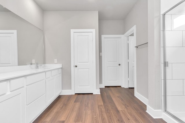 bathroom with baseboards, a shower stall, vanity, and wood finished floors