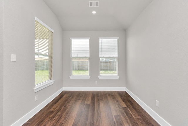 unfurnished room featuring lofted ceiling, baseboards, visible vents, and dark wood-style flooring