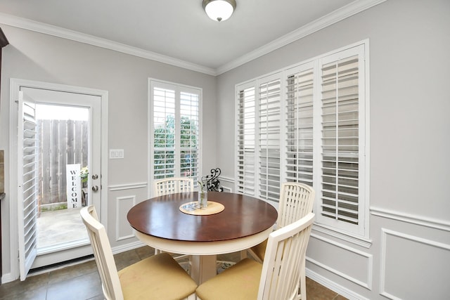 tiled dining area featuring ornamental molding, a wainscoted wall, and a decorative wall