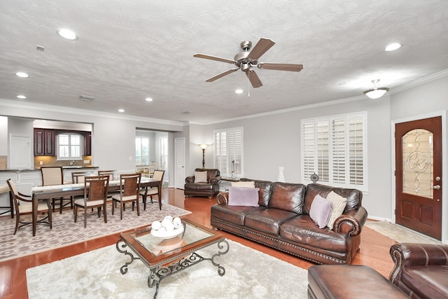 living area featuring ornamental molding, recessed lighting, a textured ceiling, and wood finished floors