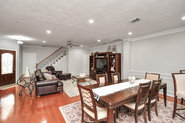 dining area with stairway, a textured ceiling, visible vents, and wood finished floors