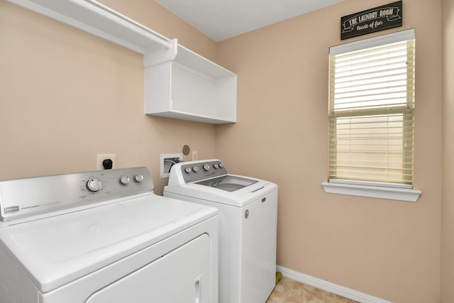 washroom featuring washing machine and dryer, laundry area, baseboards, and light tile patterned floors