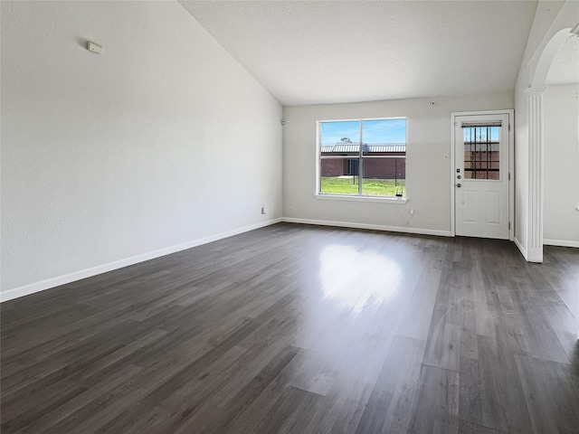 8611 Deep Valley Dr, Houston, TX 77044 - interior space with arched walkways, a textured ceiling, lofted ceiling, dark wood-style flooring, and baseboards