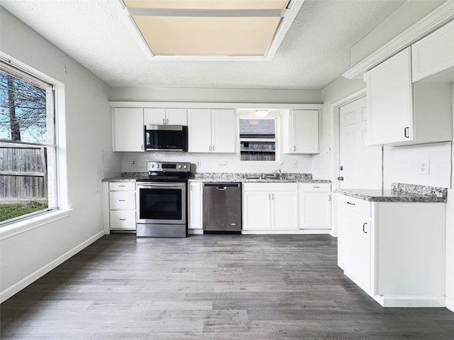 8611 Deep Valley Dr, Houston, TX 77044 - kitchen with stainless steel appliances, white cabinets, a sink, and wood finished floors