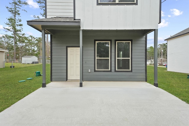 exterior space featuring a yard, a shingled roof, board and batten siding, and a patio