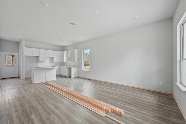 unfurnished living room with baseboards, a sink, visible vents, and light wood-style floors