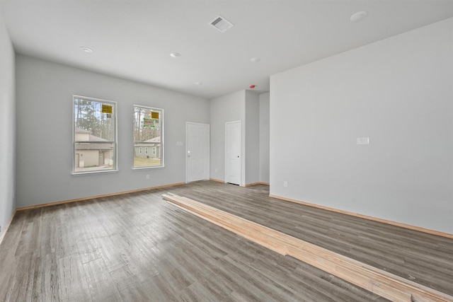 unfurnished room with wood finished floors, visible vents, and baseboards