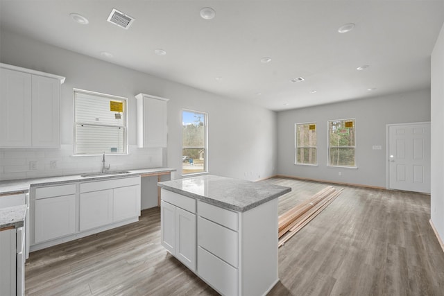 kitchen featuring tasteful backsplash, light wood-style flooring, a sink, and visible vents