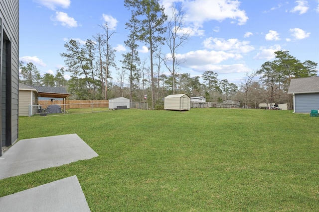 view of yard with an outbuilding, a storage unit, and a fenced backyard