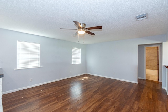 empty room featuring dark wood-style floors, a textured ceiling, visible vents, and baseboards