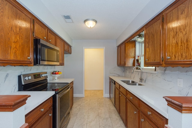 kitchen with stainless steel appliances, light countertops, a sink, and visible vents