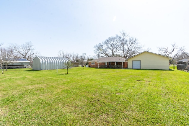 view of yard featuring a garage, an outdoor structure, and fence