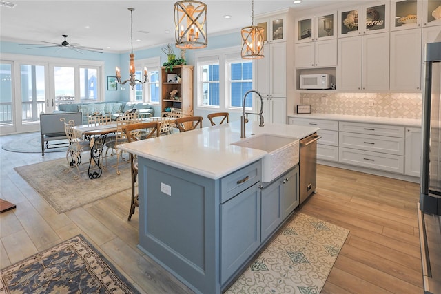 kitchen with tasteful backsplash, dishwasher, white microwave, open floor plan, and a sink