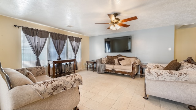 living room featuring light tile patterned floors, a textured ceiling, visible vents, and a ceiling fan