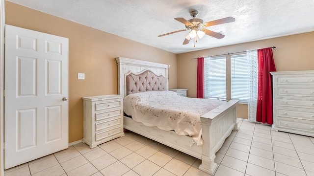 bedroom with light tile patterned floors, ceiling fan, baseboards, and a textured ceiling