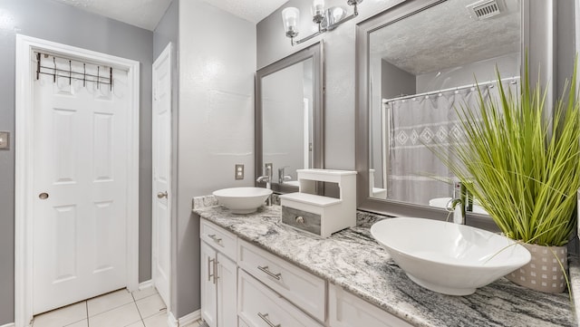 full bathroom featuring a sink, a textured ceiling, tile patterned flooring, and visible vents