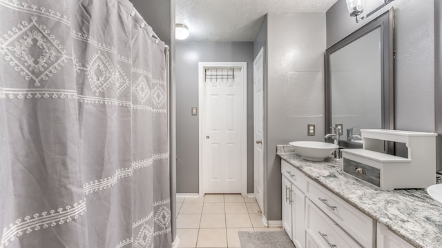 bathroom with a textured ceiling, a shower with shower curtain, vanity, baseboards, and tile patterned floors