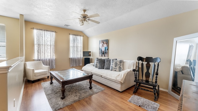 living room featuring a textured ceiling, visible vents, and wood finished floors