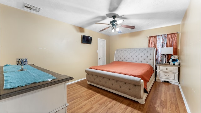 bedroom with light wood-style floors, visible vents, baseboards, and a ceiling fan