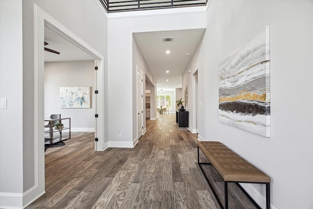 hall featuring baseboards, visible vents, wood finished floors, and recessed lighting