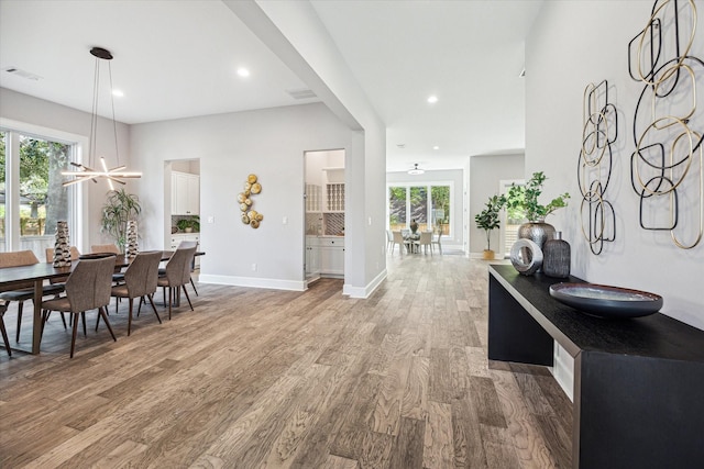 dining area featuring visible vents, plenty of natural light, light wood-style flooring, and a notable chandelier