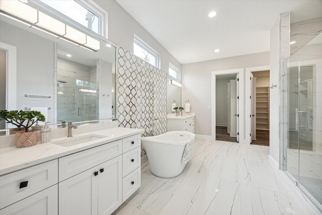 full bath featuring a stall shower, a sink, marble finish floor, a spacious closet, and two vanities