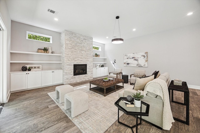 living area featuring recessed lighting, a fireplace, wood finished floors, visible vents, and built in features