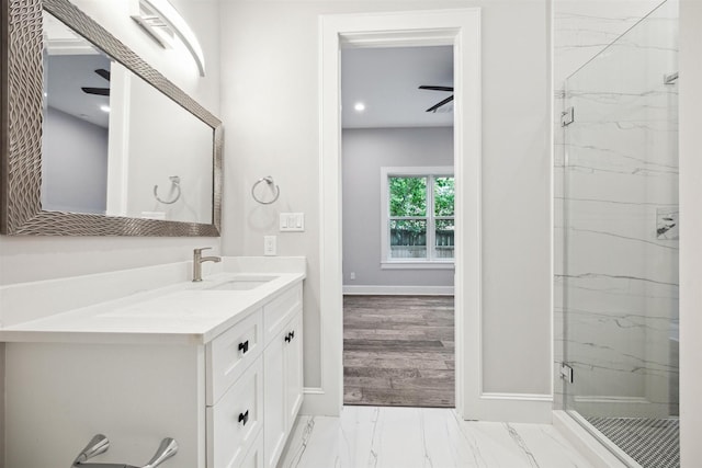 full bathroom featuring marble finish floor, a marble finish shower, vanity, and baseboards