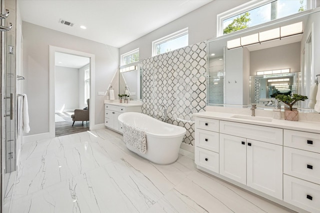 bathroom featuring a soaking tub, a sink, marble finish floor, a tile shower, and two vanities