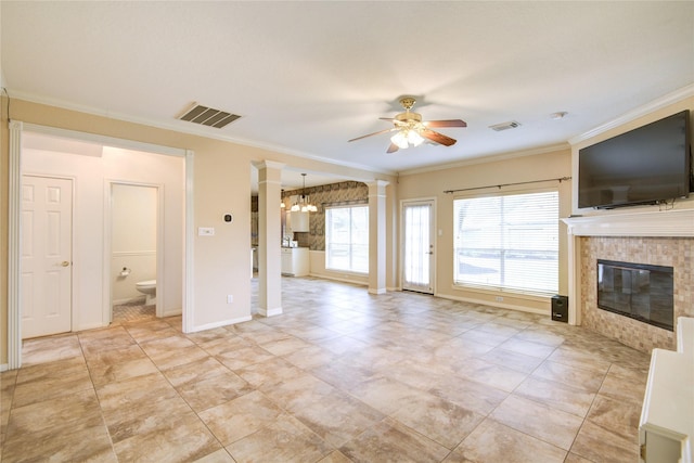 unfurnished living room featuring ornamental molding, visible vents, a fireplace, and ornate columns