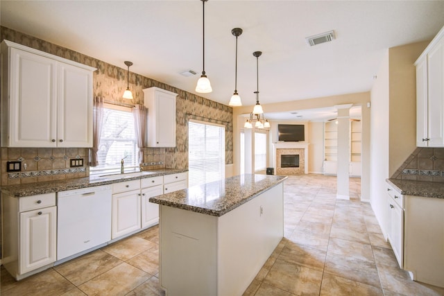 kitchen featuring a kitchen island, a sink, visible vents, white cabinets, and dishwasher