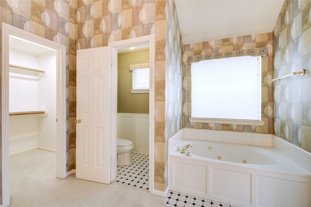 full bath with a jetted tub, toilet, and wainscoting