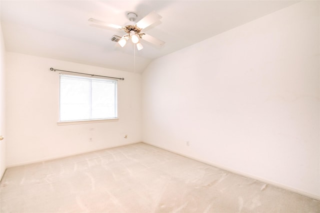 spare room featuring light carpet, vaulted ceiling, a ceiling fan, and baseboards