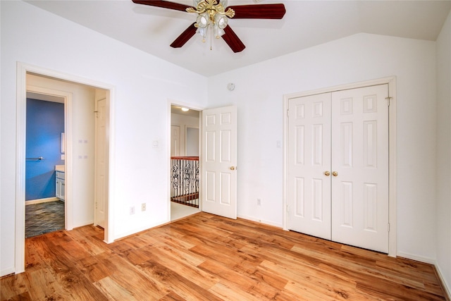 unfurnished bedroom with light wood-style floors, baseboards, vaulted ceiling, and a closet