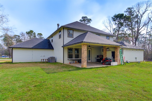 rear view of property with central AC unit, a lawn, ceiling fan, roof with shingles, and a patio area