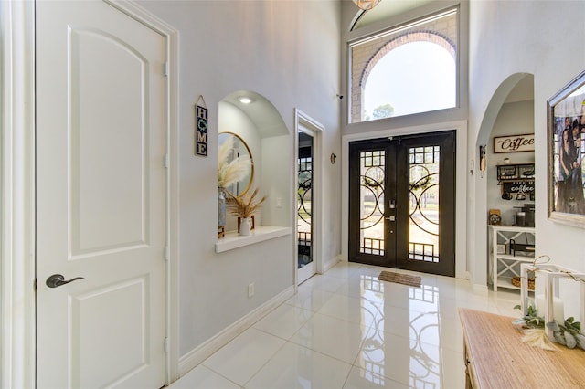 entryway with a high ceiling, baseboards, arched walkways, and french doors