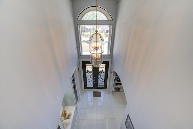 foyer entrance with a healthy amount of sunlight, light tile patterned floors, a high ceiling, and a chandelier